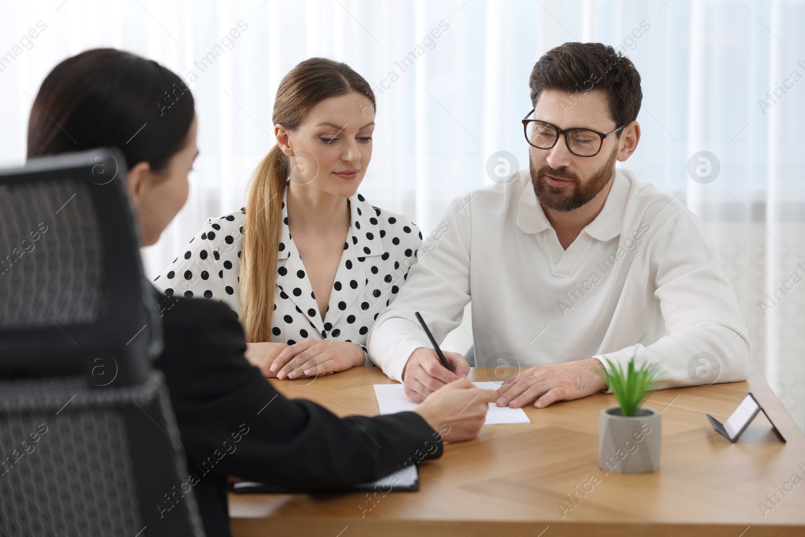 Photo of Couple signing document while having meeting with lawyer in office