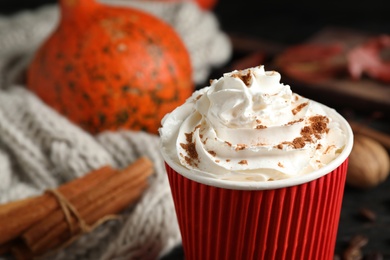 Paper cup with tasty pumpkin spice latte on table, closeup