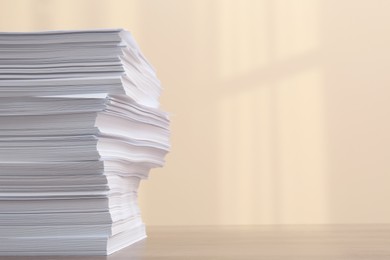 Photo of Stack of paper sheets on white wooden table against beige background. Space for text