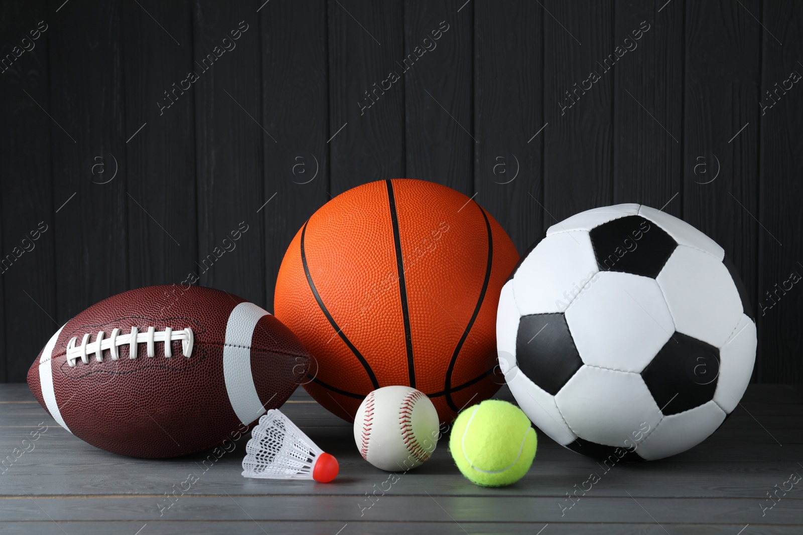 Photo of Set of different sport balls and shuttlecock on grey wooden table