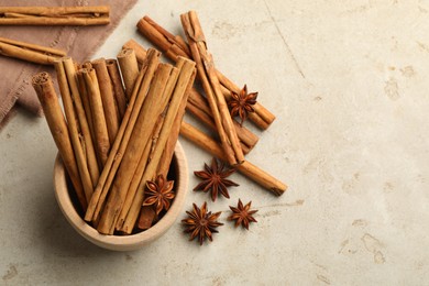 Bowl with cinnamon sticks and star anise on light table, flat lay. Space for text