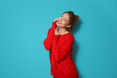 Beautiful young woman in warm sweater on color background