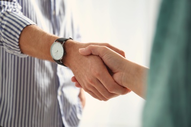 Photo of Man and woman shaking hands on light background, closeup. Help and support concept