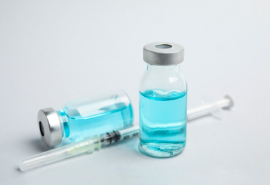 Vials and syringe on light background. Vaccination and immunization