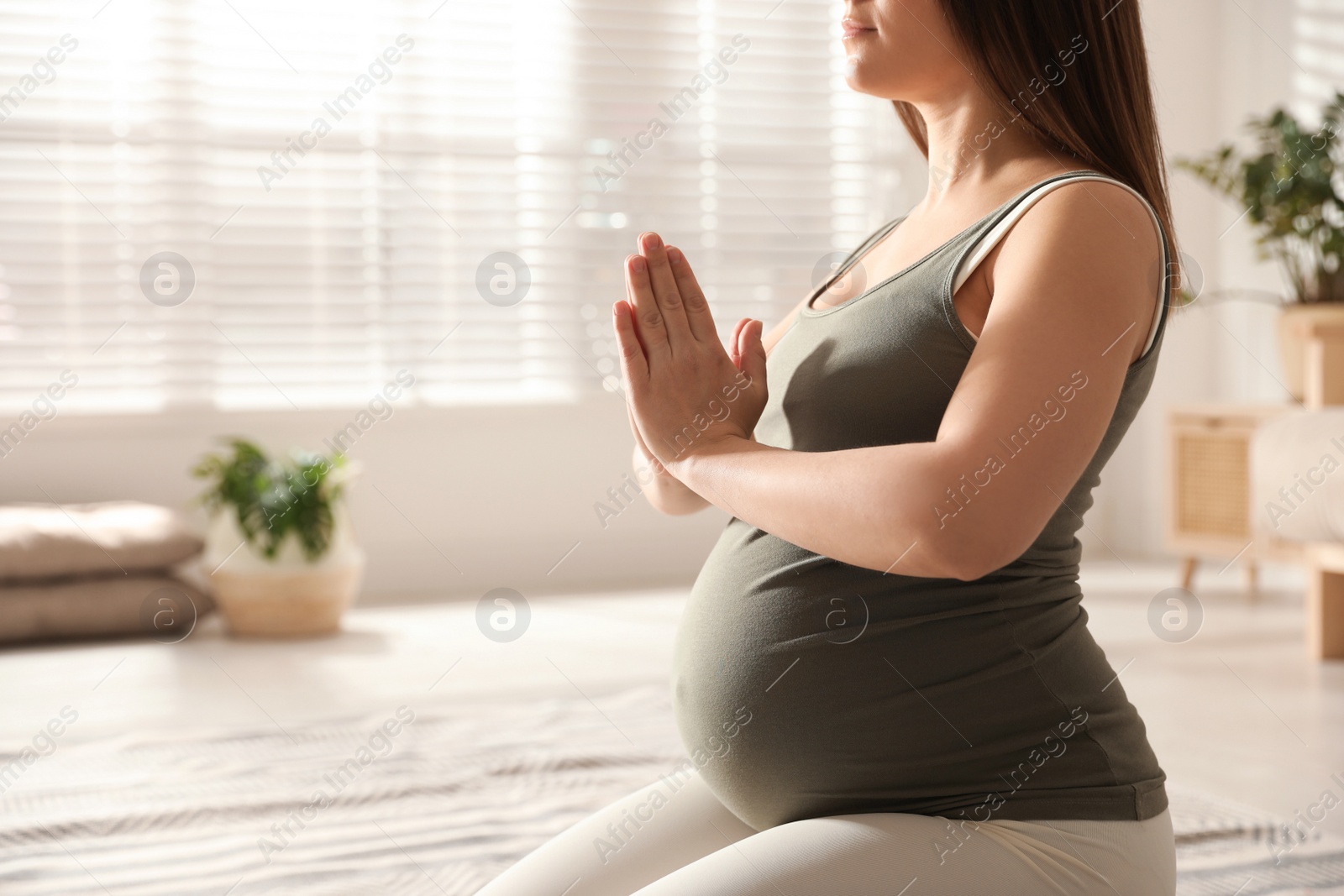 Photo of Young pregnant woman practicing yoga at home, closeup. Space for text