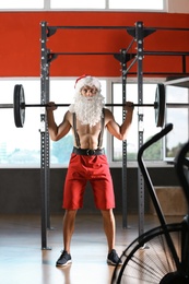 Young muscular man in Santa costume training at gym