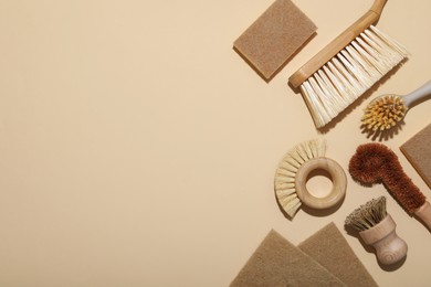 Photo of Cleaning brushes and sponges on beige background, flat lay. Space for text