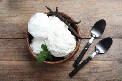 Yummy vanilla ice cream served on wooden table, flat lay