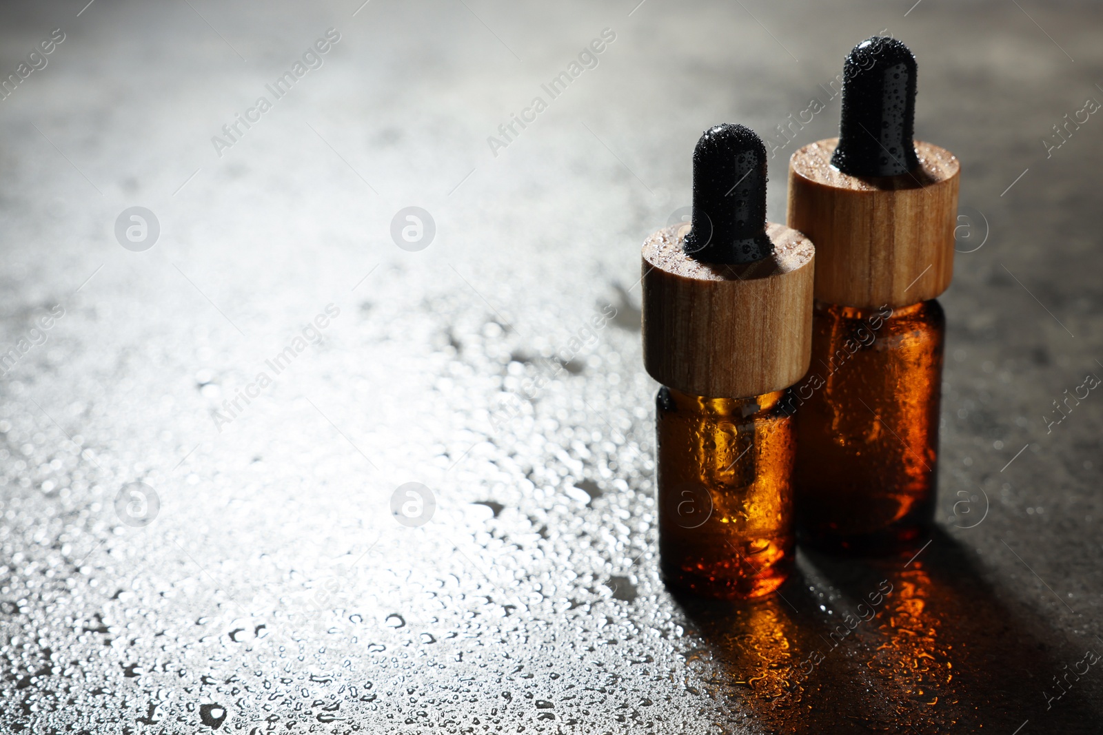 Photo of Bottles of cosmetic product on grey wet background. Space for text
