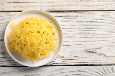 Photo of Plate of cooked spaghetti squash on wooden table, top view with space for text