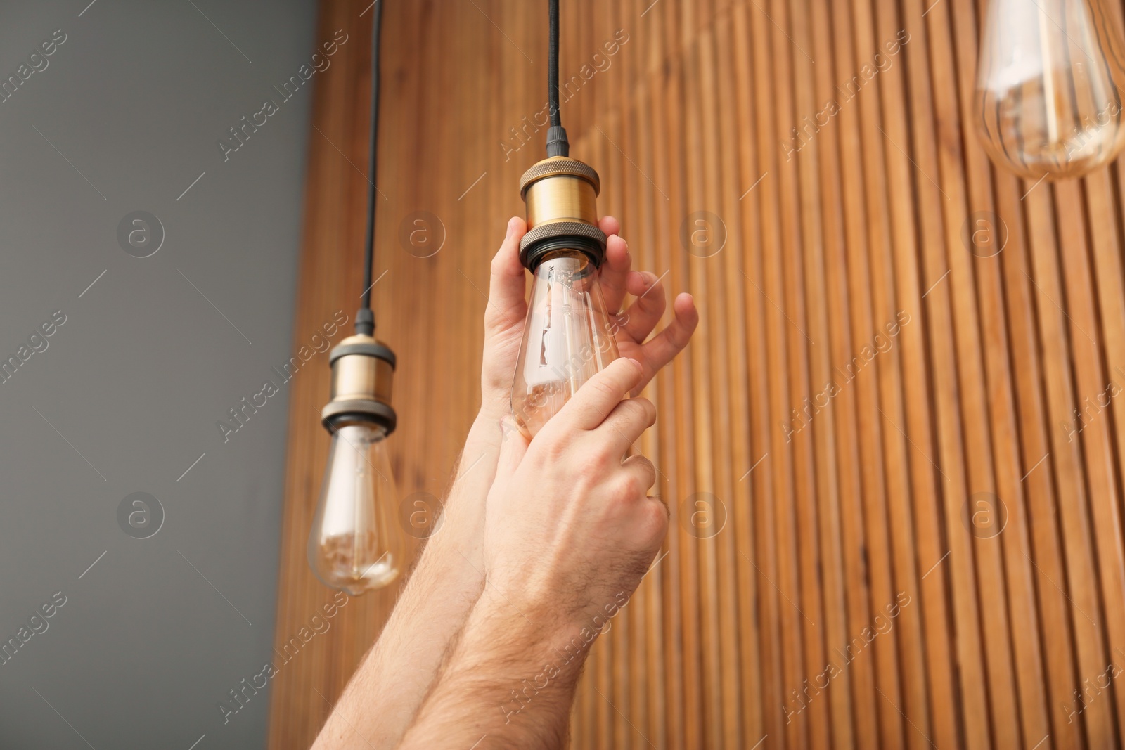 Photo of Man changing lamp light bulb indoors, closeup