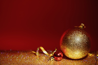 Photo of Golden glitter, Christmas balls and streamer against color background. Space for text