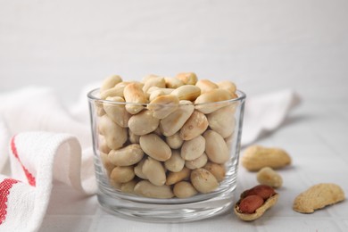 Photo of Roasted peanuts in bowl on white table, closeup