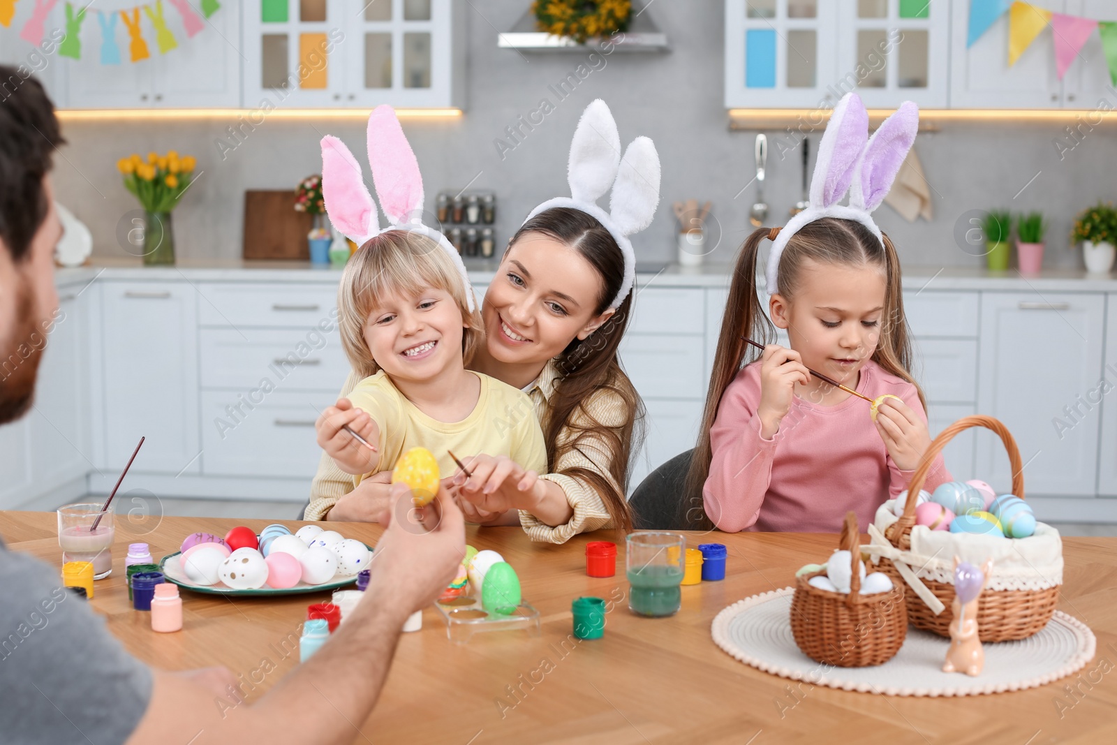 Photo of Happy family painting Easter eggs at table in kitchen