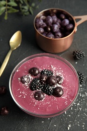 Photo of Bowl of tasty acai smoothie on dark table