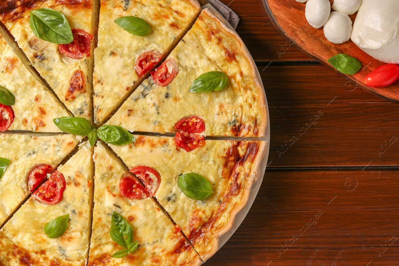 Photo of Delicious homemade cheese quiche and ingredients on wooden table, flat lay