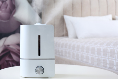 Photo of Modern air humidifier on table indoors. Space for text