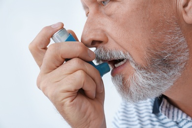 Photo of Man using asthma inhaler on white background, closeup