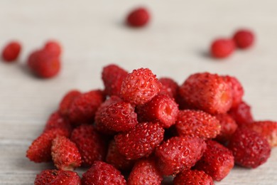 Photo of Pile of wild strawberries on white wooden table, closeup