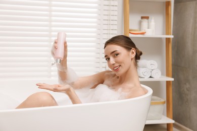 Photo of Woman pouring shower gel onto hand in bath indoors