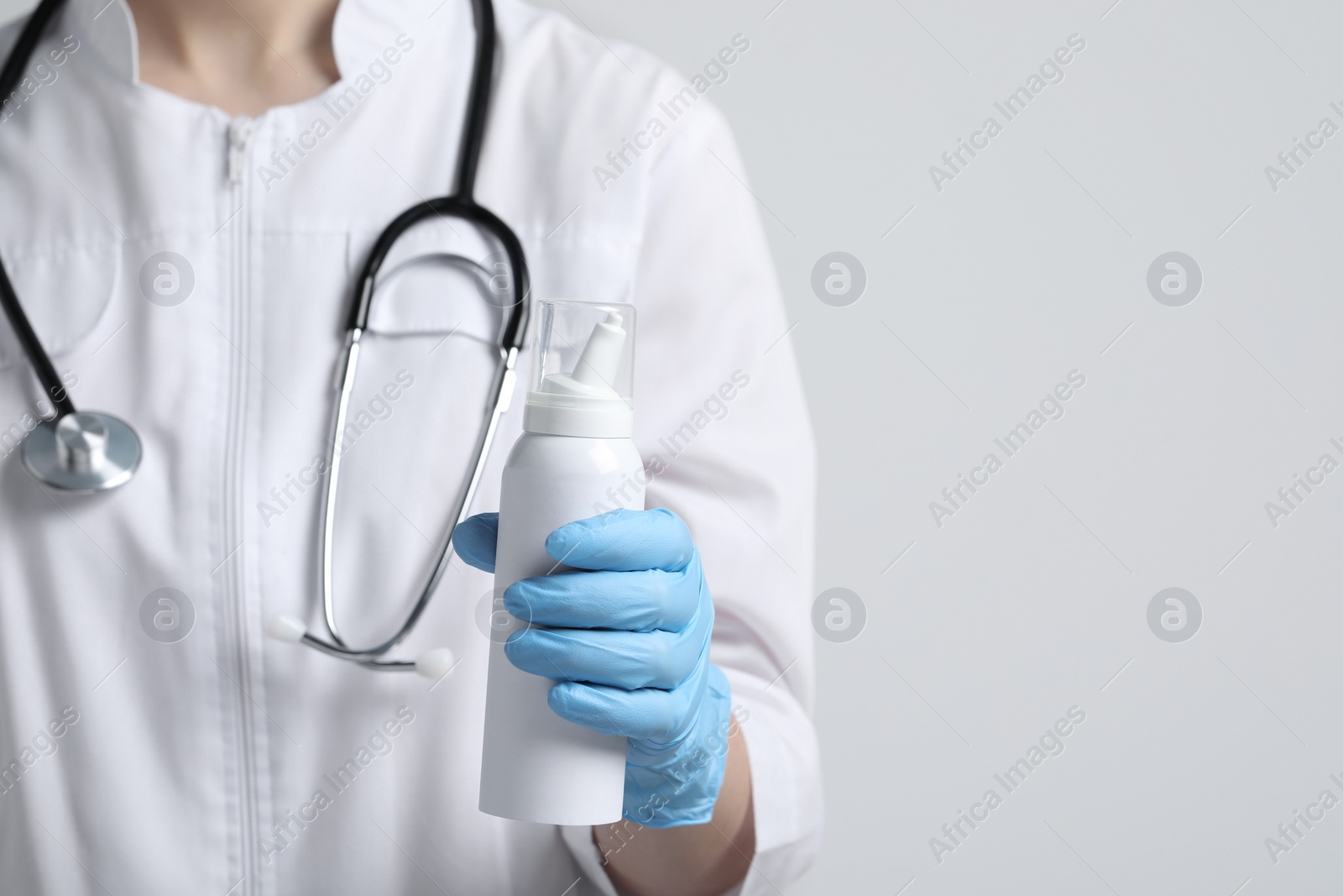 Photo of Doctor holding nasal spray on white background, closeup. Space for text