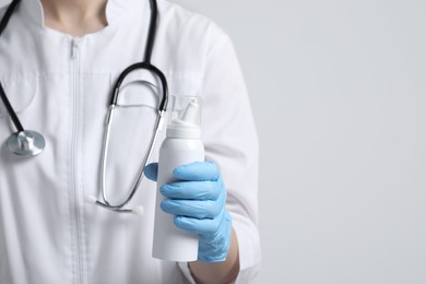 Doctor holding nasal spray on white background, closeup. Space for text