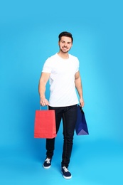 Photo of Full length portrait of young man with paper bags on blue background