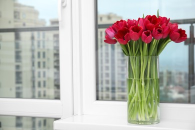 Bouquet of beautiful tulips in glass vase on window sill indoors. Space for text