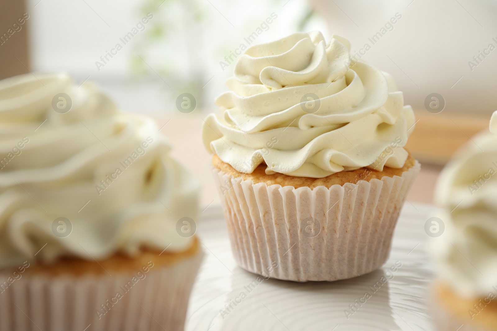 Photo of Tasty cupcakes with vanilla cream on table, closeup