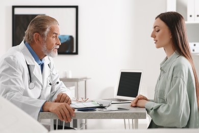 Photo of Professional orthopedist consulting patient at table in clinic