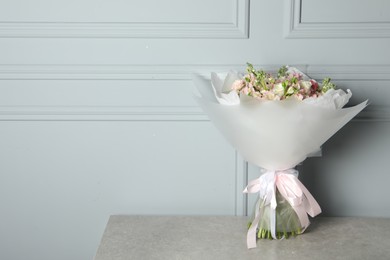 Beautiful bouquet of fresh flowers on table near grey wall, space for text