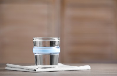 Glass of clean water on wooden table indoors, space for text