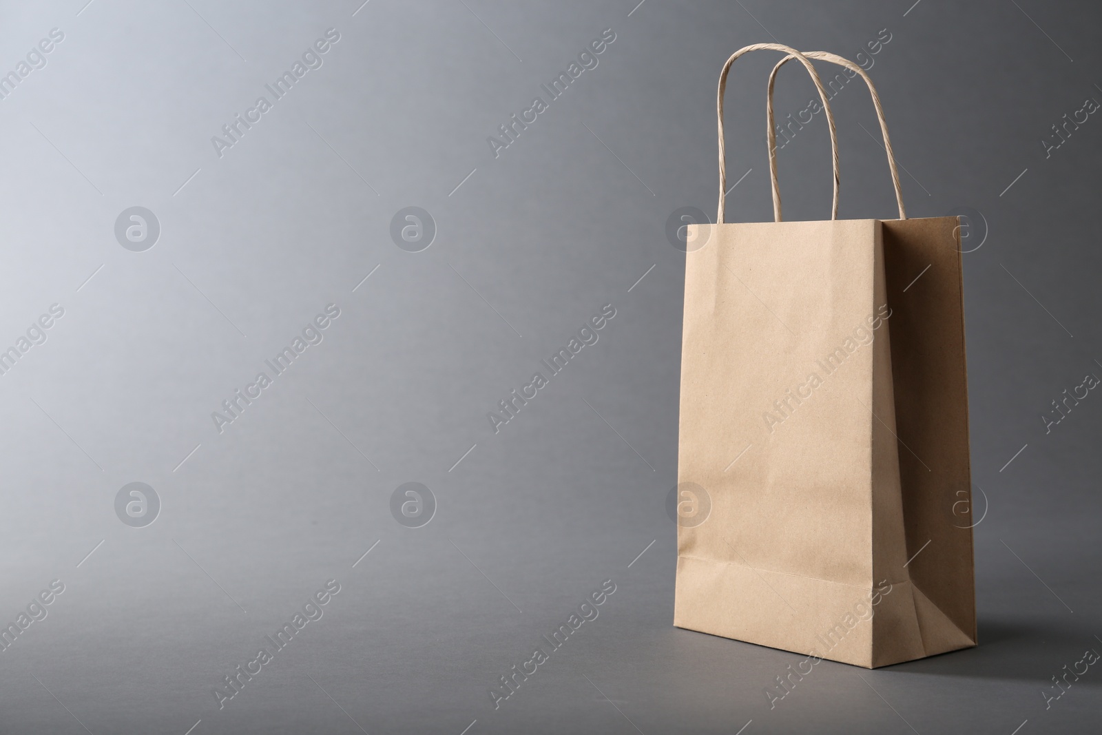 Photo of One kraft paper bag on grey background, space for text. Mockup for design