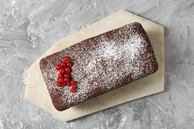 Photo of Tasty chocolate sponge cake with powdered sugar and currant on grey textured table, top view