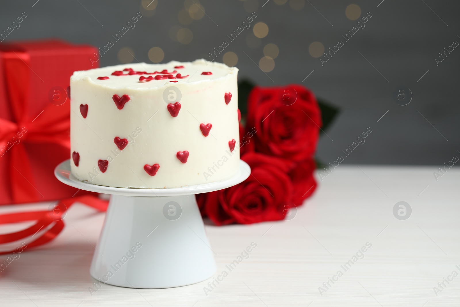 Photo of Bento cake, gift box and roses on white wooden table, space for text. St. Valentine's day surprise