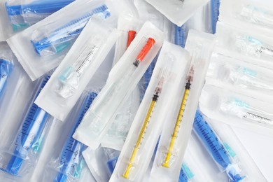 Packed disposable syringes with needles on white background, top view