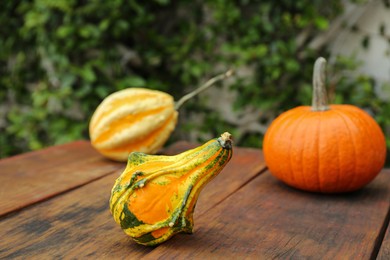 Photo of Fresh ripe pumpkins on wooden table outdoors