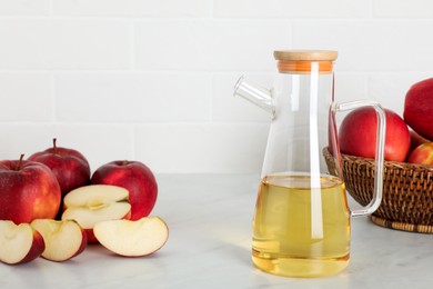 Photo of Natural apple vinegar and fresh fruits on white marble table