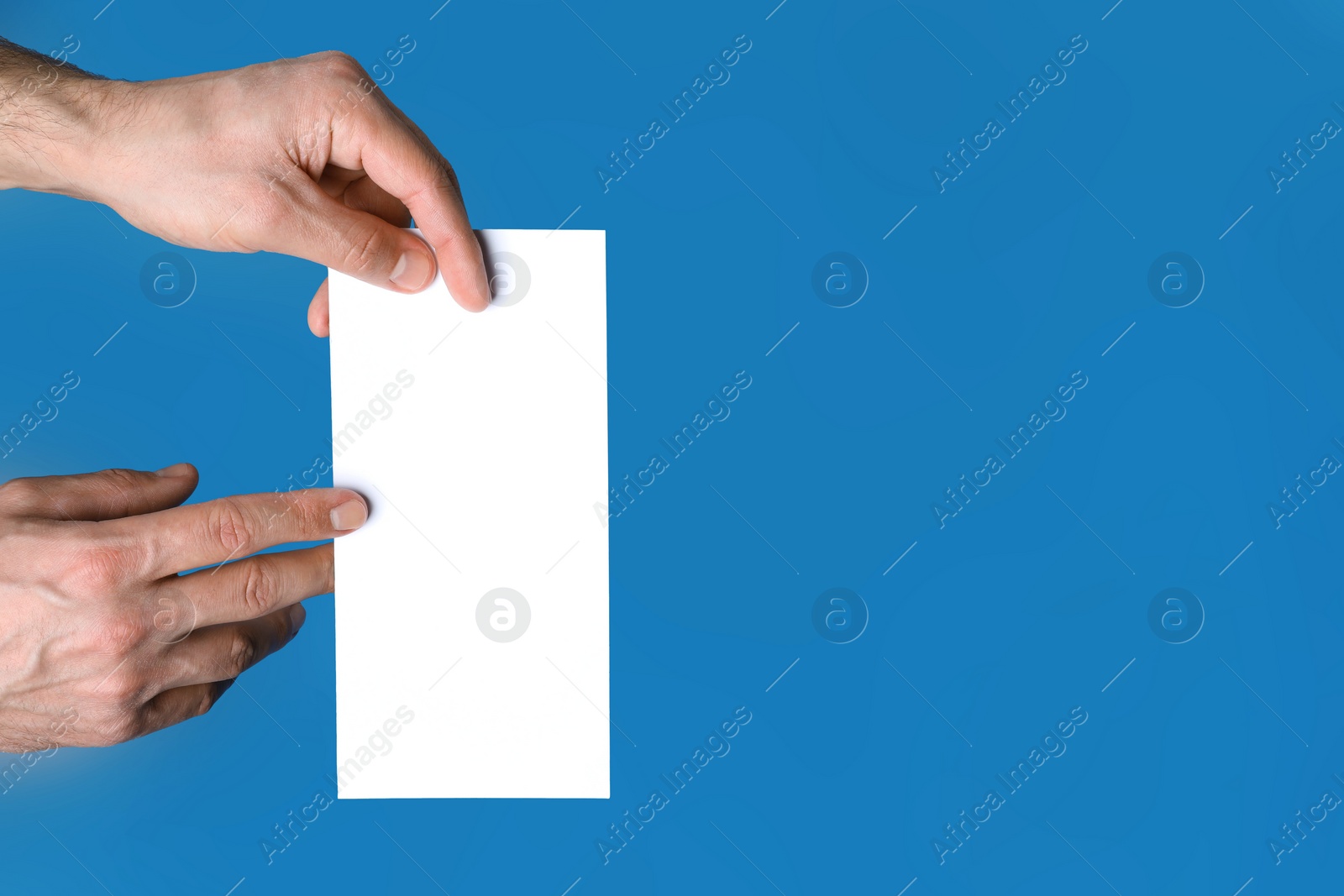 Photo of Man holding flyer on blue background, closeup. Mockup for design