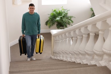 Photo of Handsome man with suitcases going up stairs in hotel