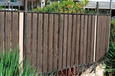Metal and wooden fence outdoors on sunny day
