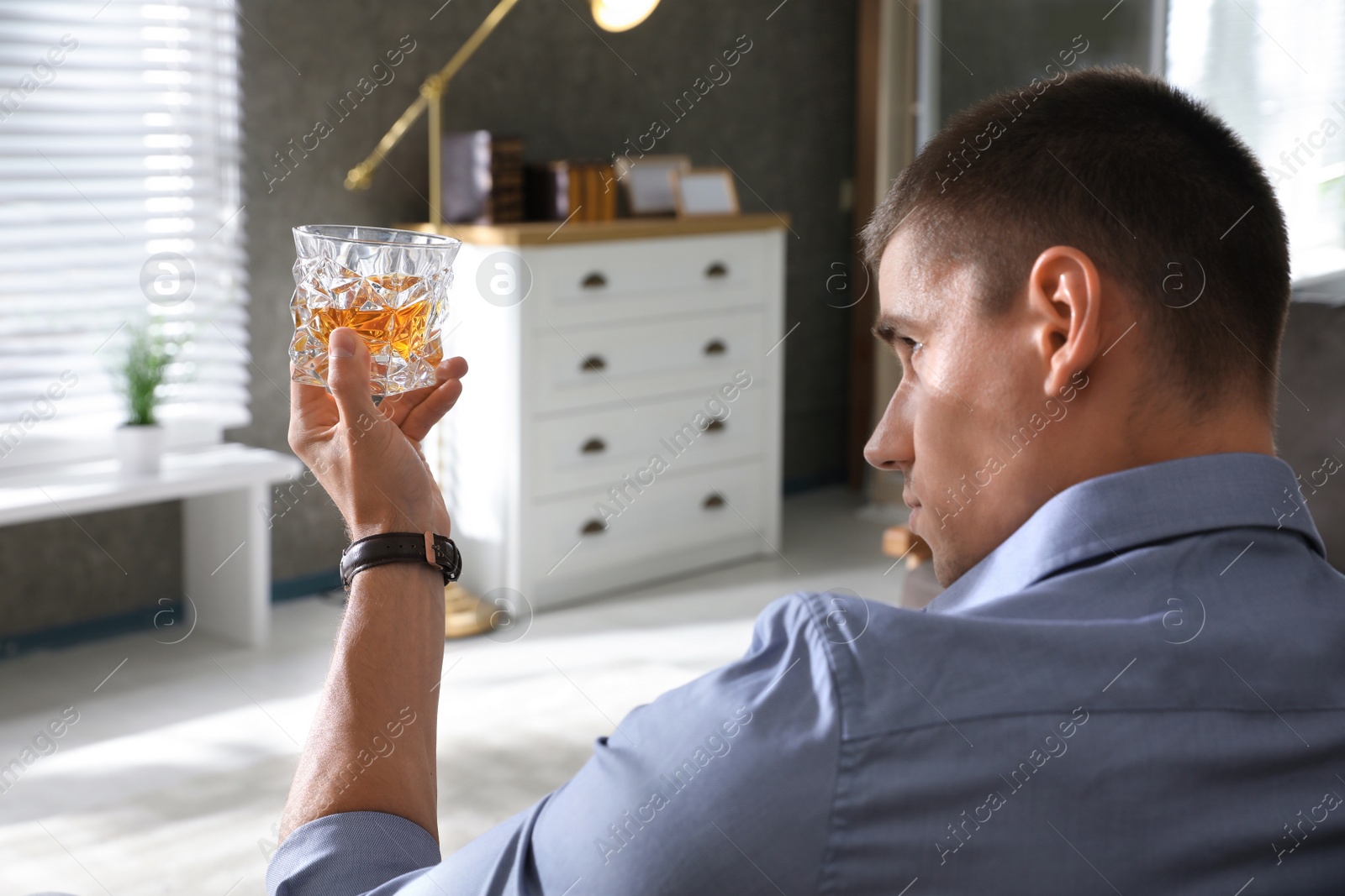 Photo of Young man with glass of whiskey at home