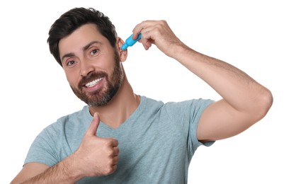 Photo of Man using ear drops and showing thumbs up on white background