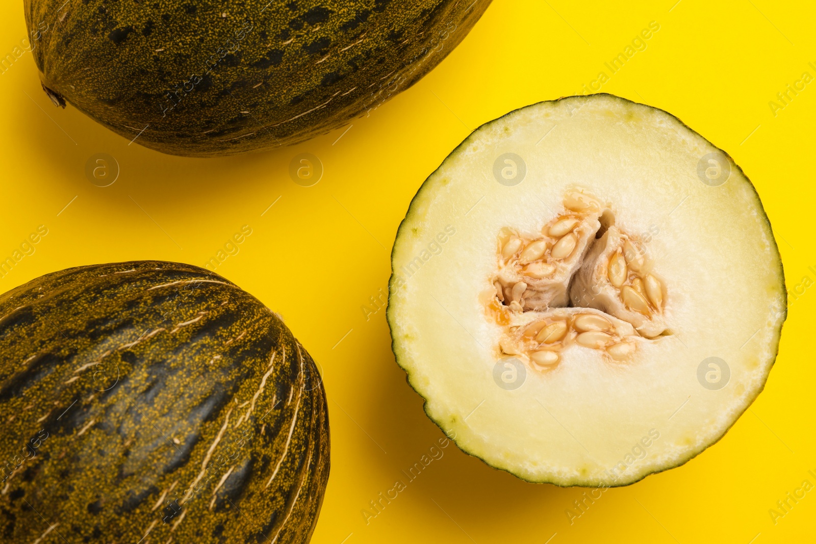 Photo of Ripe tasty melons on yellow background, flat lay