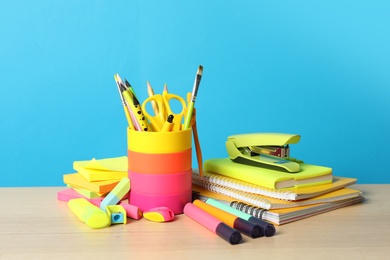 Photo of Composition with different school stationery on wooden table against light blue background. Back to school