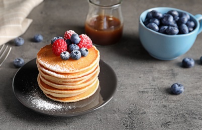Photo of Tasty pancakes with berries and sugar powder on plate