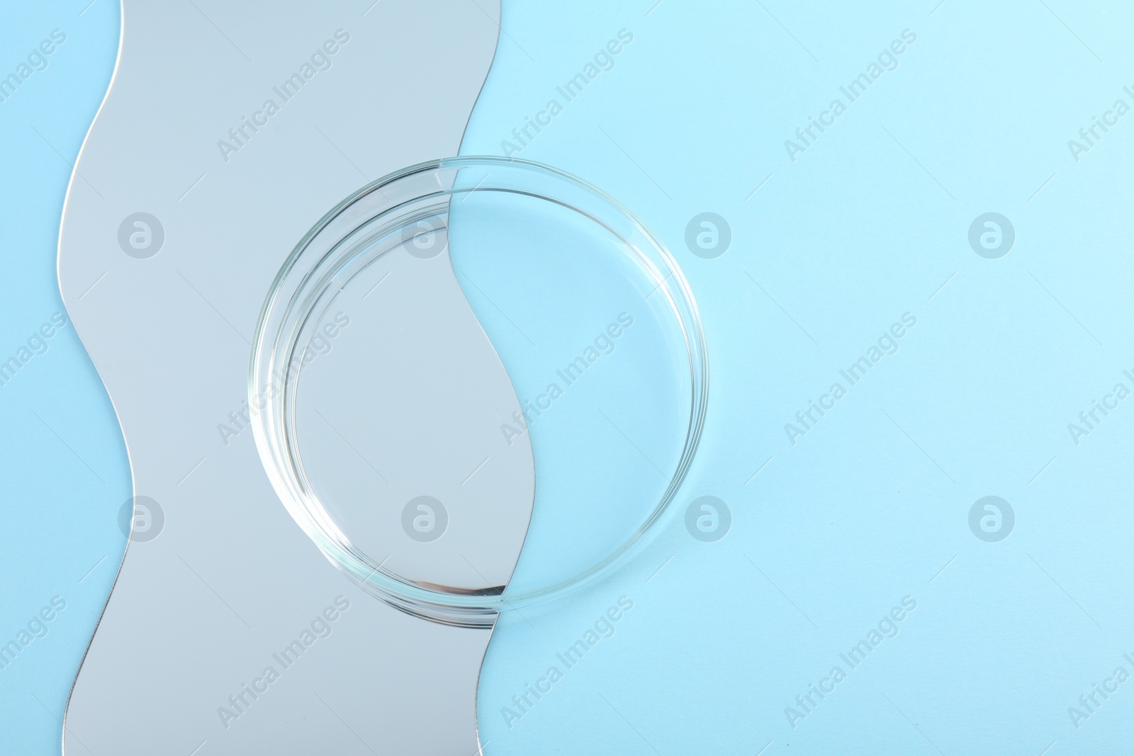 Photo of Empty petri dish and mirror on light blue background, flat lay. Space for text