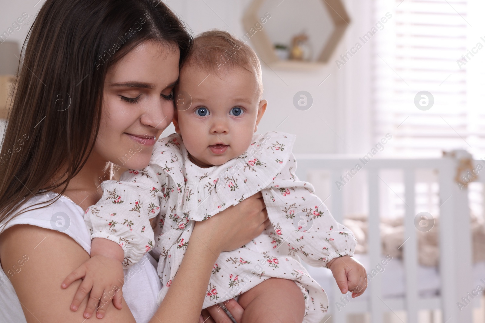 Photo of Happy young mother with her baby daughter in nursery. Space for text