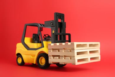 Toy forklift with wooden pallets on red background