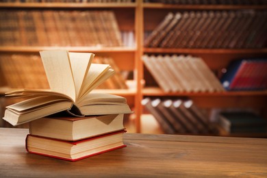 Many books on wooden table in library. Space for text 